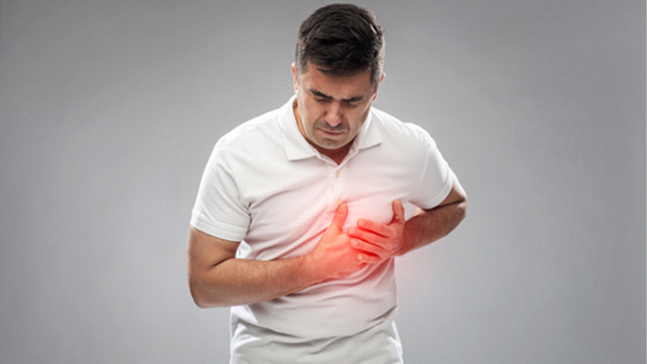 Man in white polo shirt experiencing a heart attack 