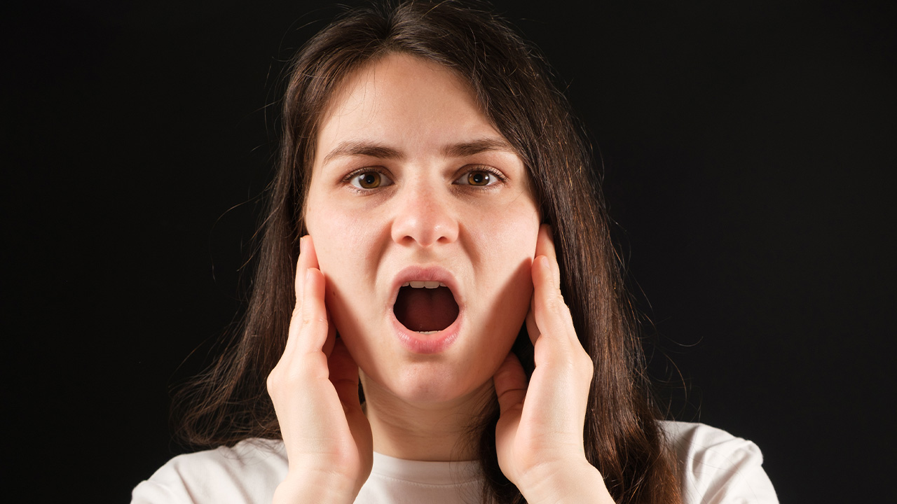 Close-up of woman in white shirt with TMJ disorder